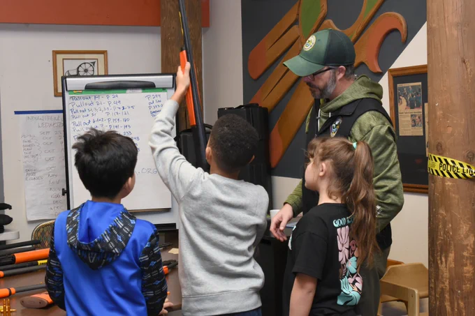 Photo by WDFW: R3 (Recruit, Retain, Reactivate) Hunting Coordinator Kelly Riordan shows youth members of the Skokomish Indian Tribe safe firearm handling.