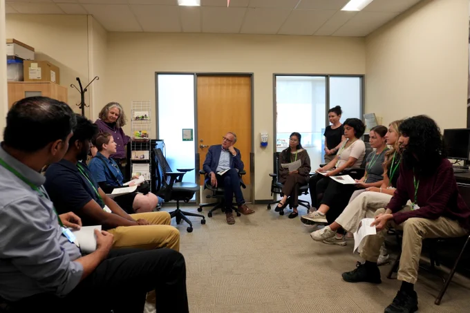 MP Rob Oliphant seated, participating in a conversation with students in an office at Holland Bloorview