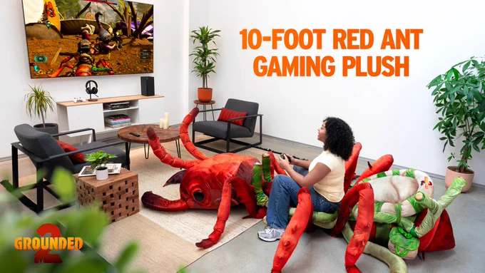 Image of a person playing a video game while sitting on a giant red ant plush. The screen shows a scene from Grounded 2, and large text says “10-FOOT RED ANT GAMING PLUSH” in the top right corner. The Grounded 2 logo is in the bottom left corner.