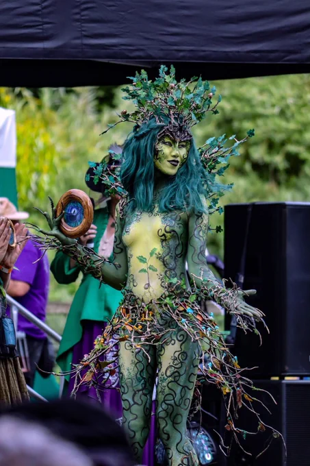 Oak Dryad Bodypainting look, with tree branches fashioned into a collar and headdress. Pale green stomach with an oak sapling and dark green lbs. with swirling painted branches around the arms.