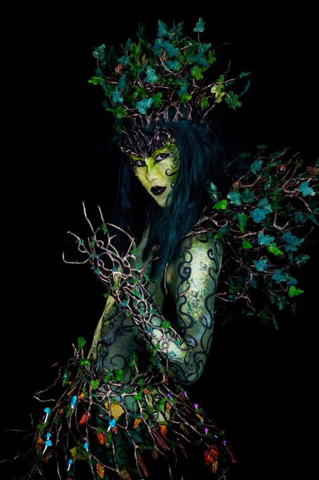 Oak Dryad Bodypainting look, with tree branches fashioned into a collar and headdress. Pale green stomach with an oak sapling and dark green lbs. with swirling painted branches around the arms.