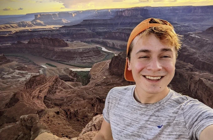 young man with orange baseball cap overlooking a canyon

