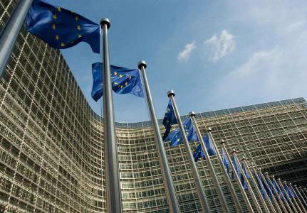 Photo of the European Commission building with European Union flags lined up in front.