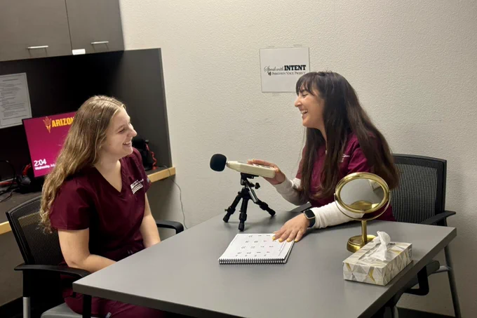 Two students in training at the Speech and Hearing Clinic practice with a microphone.