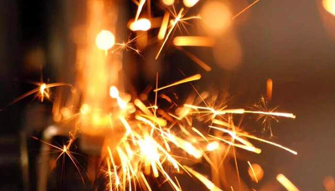 Close-up of bright sparks flying during a precision laser welding process, showcasing the intensity and accuracy of modern laser welding technology.