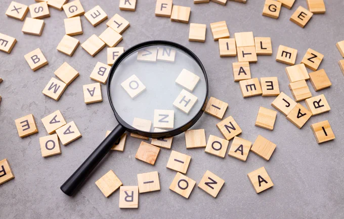 Square letter tiles with magnifying glass against blue background