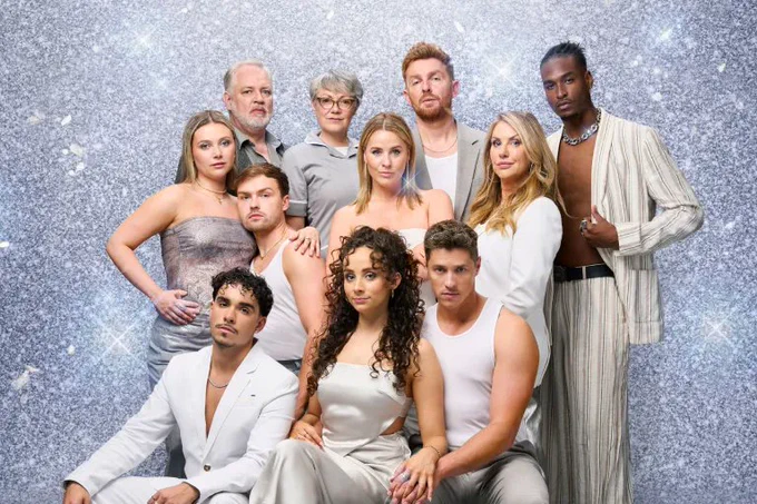 A photo showing a group of performers in silvery outfits in front of a sparkly photoboard 
