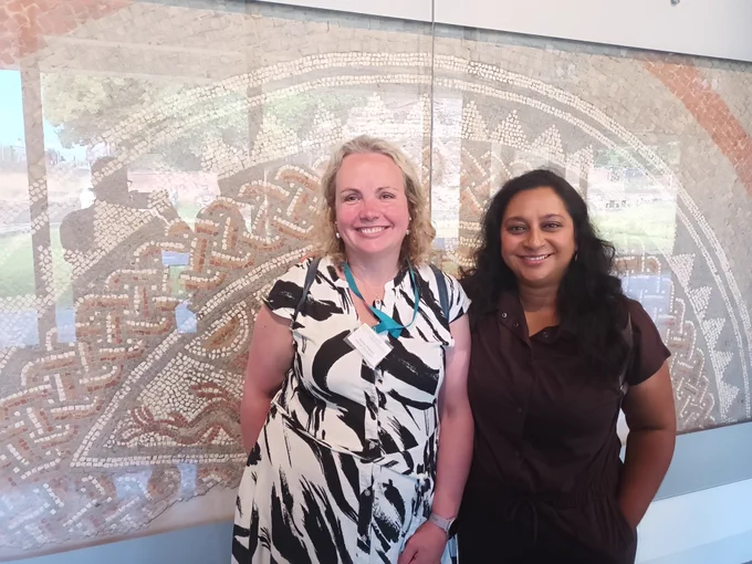 Two women in front of a mosaic