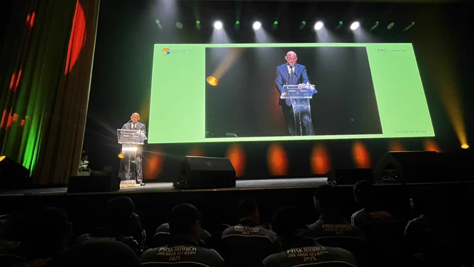 Simon Stiell, Executive Secretary of the UNFCCC, delivers a keynote address at the Indonesia Net Zero Summit 2025. He stands at a podium on a dimly lit stage, with a large screen behind him showing a close-up view. The screen’s green border displays the event branding, with lighting effects in yellow and red illuminating the scene. Mr. Stiell emphasizes the alignment of climate action and economic progress, while calling for bold plans and collective leadership from Indonesia in the clean energy transition. (Photo: UN Information Centre Jakarta/Bayu Dwityo Wicaksono)