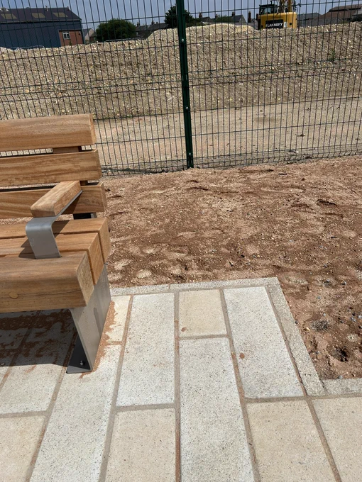A bench with arms at both ends yet extended paving around the bench that would allow for sideways transfer if the arm wasn’t there.