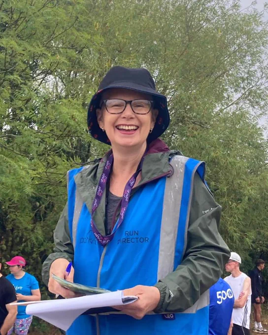 A run director wearing a bucket hat, smiling at the camera.