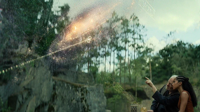 Jared Harris as Hari Seldon stands holding the Prime Radiant and pointing at the golden psychohistorical equations it's projecting in the sky. Lou Llobell as Gaal Dornick stands next to him looking at the equations with a captivated expression.