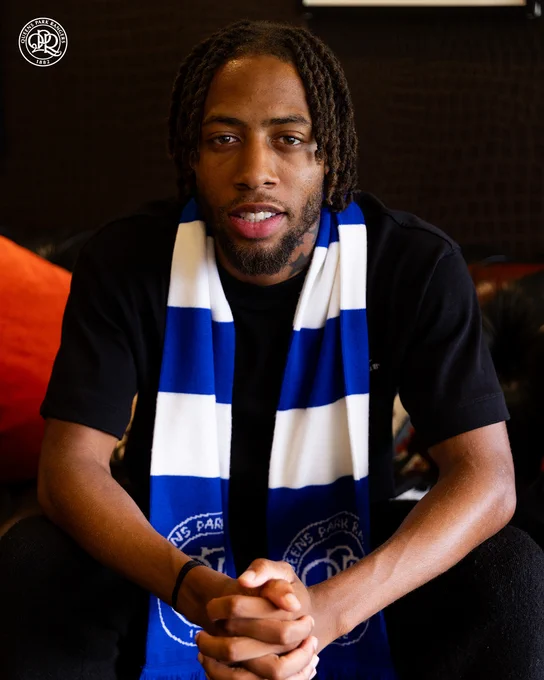 Rumarn Burrell sitting with a blue and white QPR scarf around his neck.