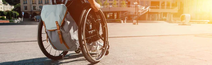 A person propelling a wheelchair from behind.