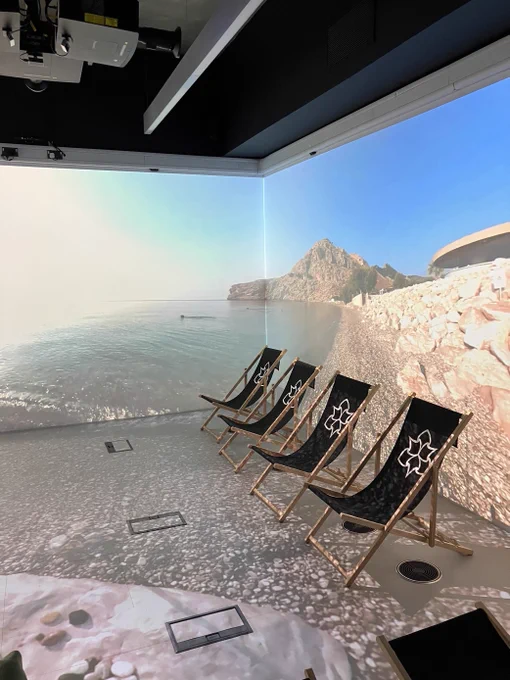 Inside the CAVE, a beach background is projected on the screens and deck chairs are out