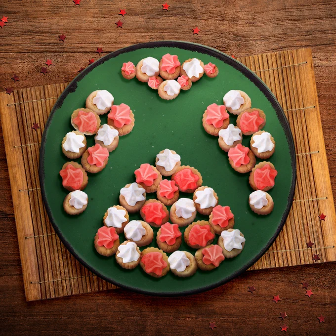 Top-down view of a green plate of pink and white gem biscuits, positioned to create
the shape of the Xbox nexus logo in the negative space.