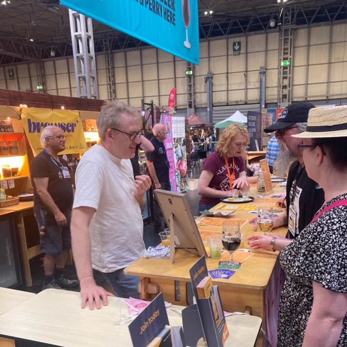 Photo of James Godman, from Wilderness, behind the Discovery Bar talking to festival goers.
