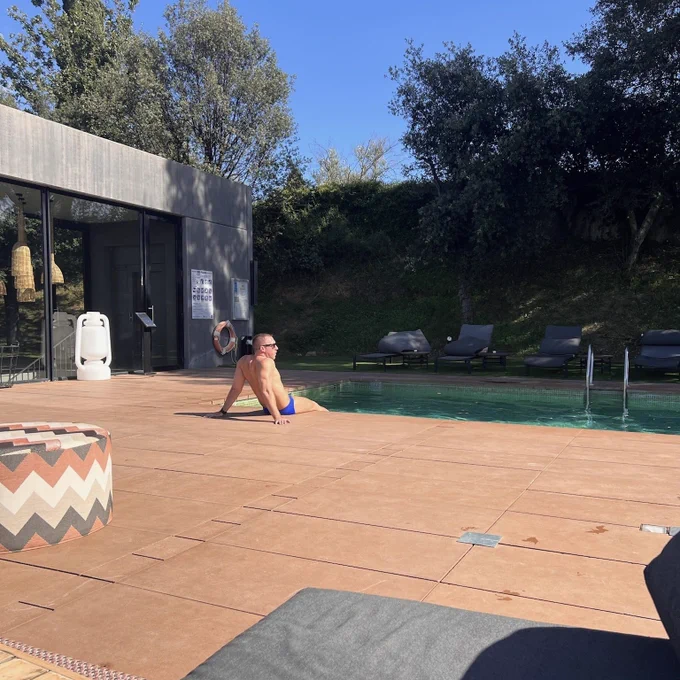Candid photo of me relaxing by the pool in Barcelona wearing a cute blue speedo.