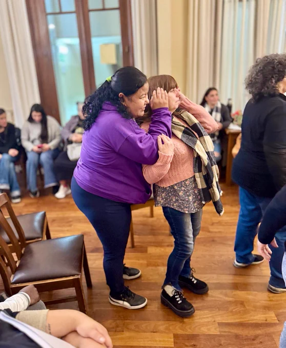 One person covering the ears of the person in front of them. They are both looking towards the front of the room.