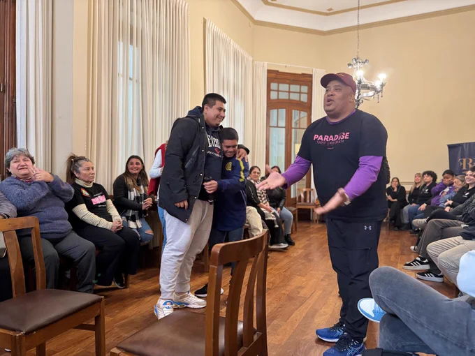 Three individuals in the center of the room acting out a roleplay scenario while the rest of the participants around the room look on.