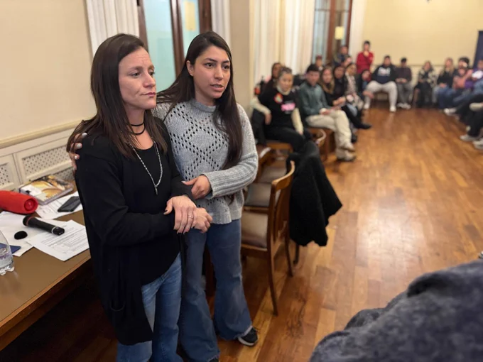 Two people, with one putting their hand on the other's shoulder for support to practice conflict mediation—while the rest of the attendees watch in the room.