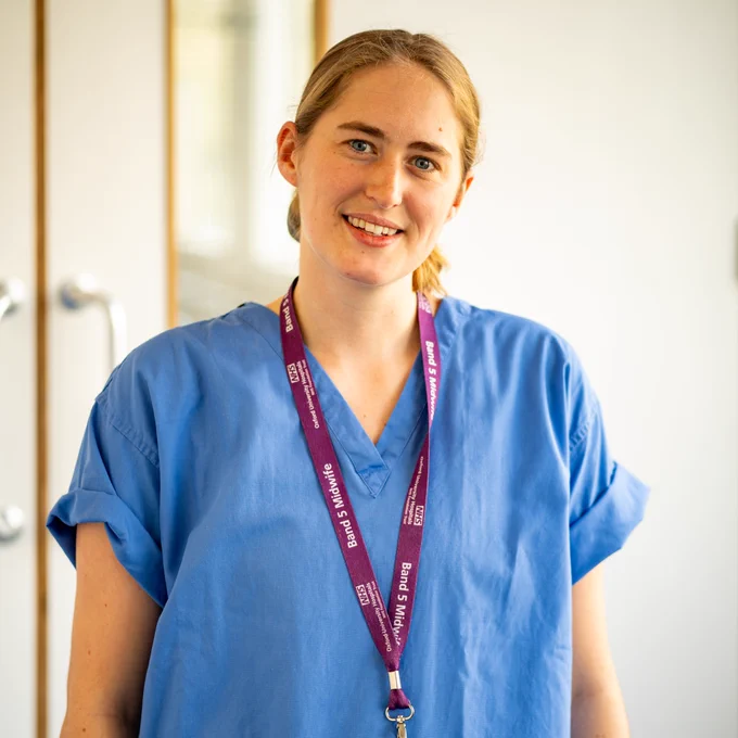 Smiling woman in lanyard and midwife's shirt