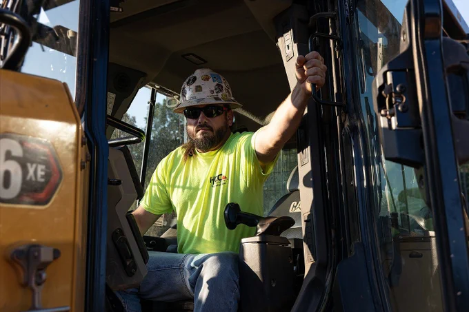 Heavy equipment operator sitting in the cabin of his caterpillar dozer with his arms crossed on a construction site in Charlotte, North Carolina.