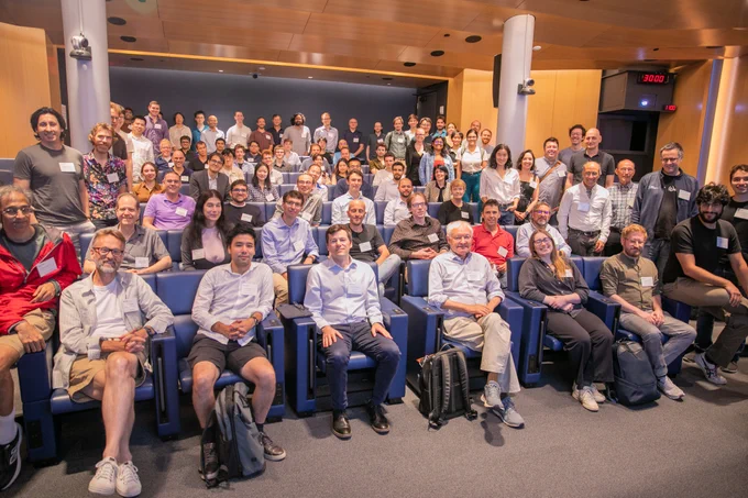 Large group of people pose for a group photo in an auditorium