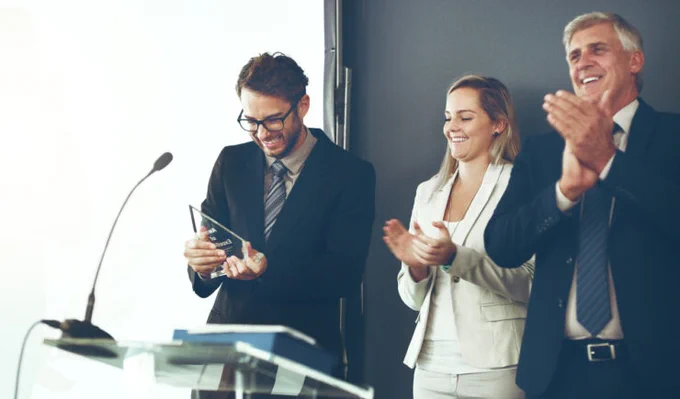One person receives an award while two others clap