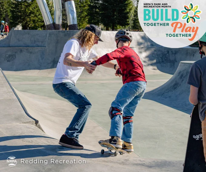 Ryan Dye, Skateboard Camp instructor, guides a young camper as they drop into the sloped bowl at Caldwell Skate Park.
