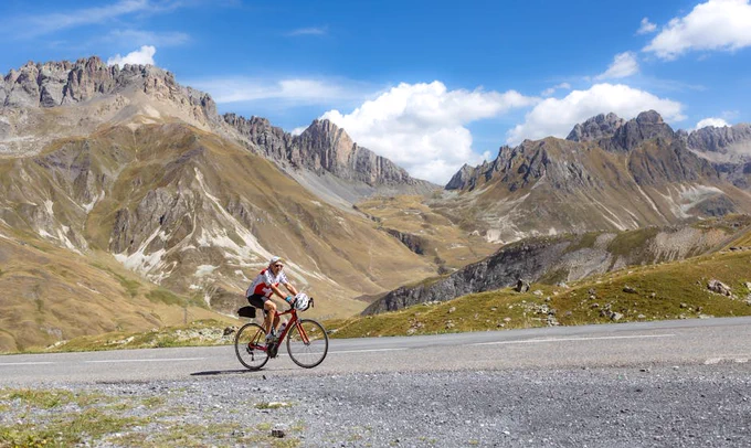 Cyclist riding on a scenic mountain road in Italy, surrounded by stunning peaks.