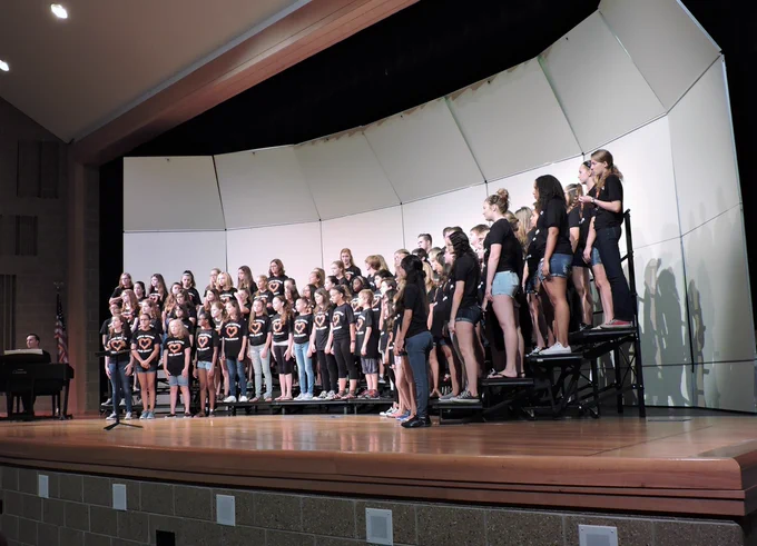 group of middle school student singers stand on risers