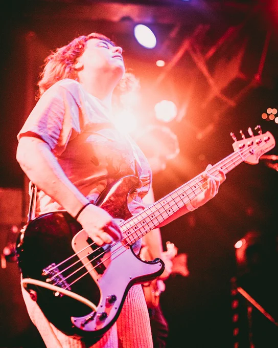 photo of Emma playing bass with burst of light behind her