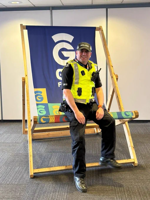A uniformed police sergeant at Glasgow Airport sitting on a giant size deck chair.