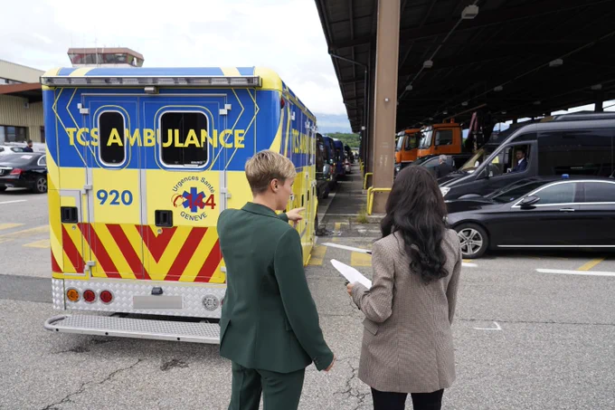 a man and woman standing in front of a yellow and blue ambulance