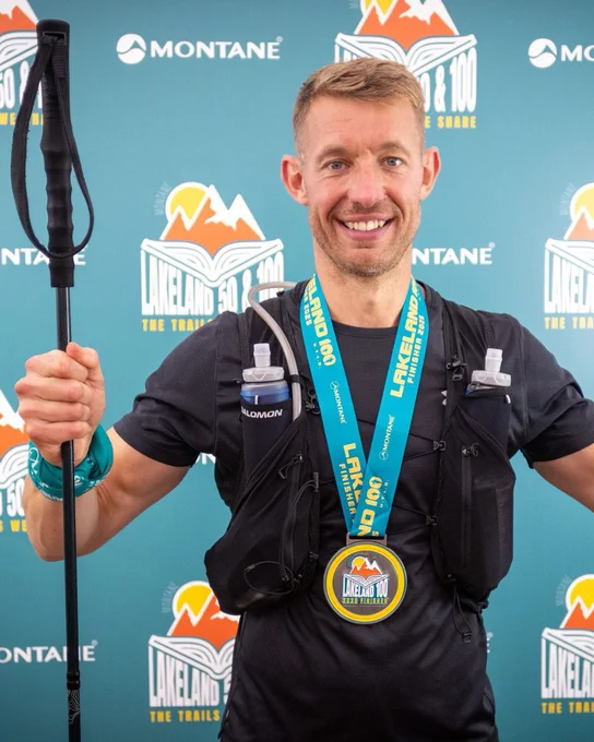 Mick wearing a medal around his neck, with drinking bottles strapped to his chest.