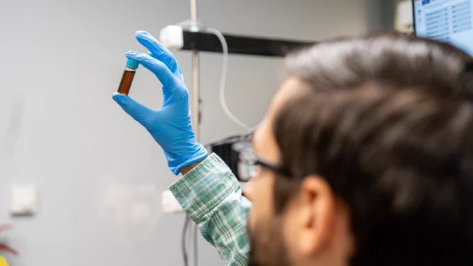 Chris Grieco holds vial in laboratory