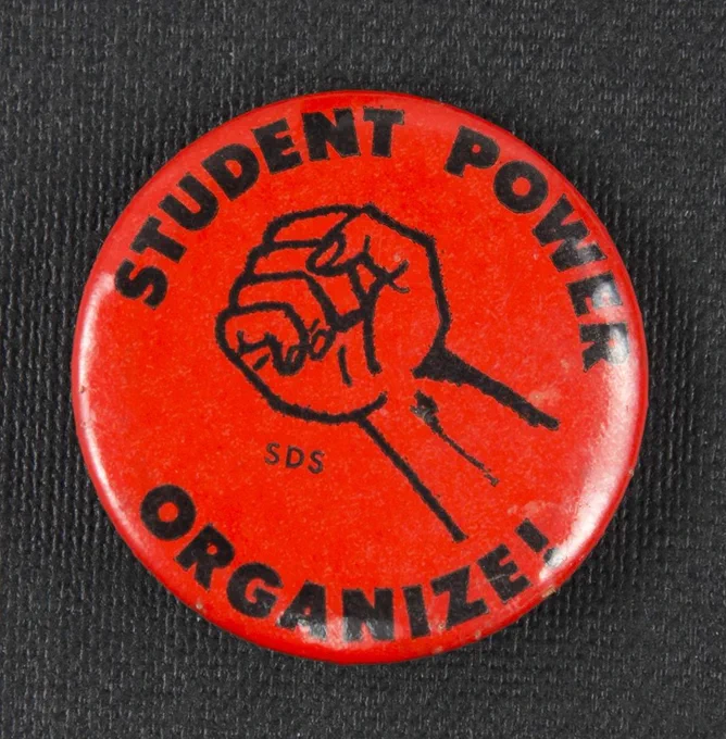round pinback button with text "Student Power Organize!" around a clenched fist with "SDS"