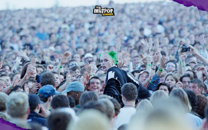 Keith Flint turning to face the camera, surrounded by fans in the crowd.