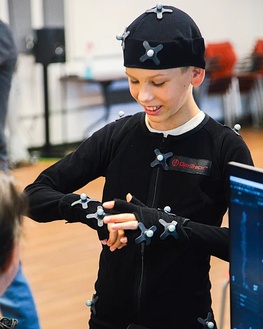 A student puts on a black motion capture suit.