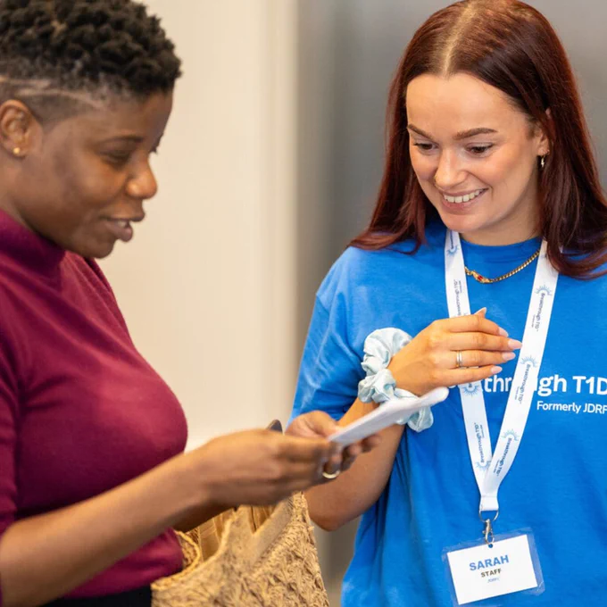 Two individuals in a conference setting, one wearing a 'Breakthrough T1D' staff t-shirt reviewing a document together.