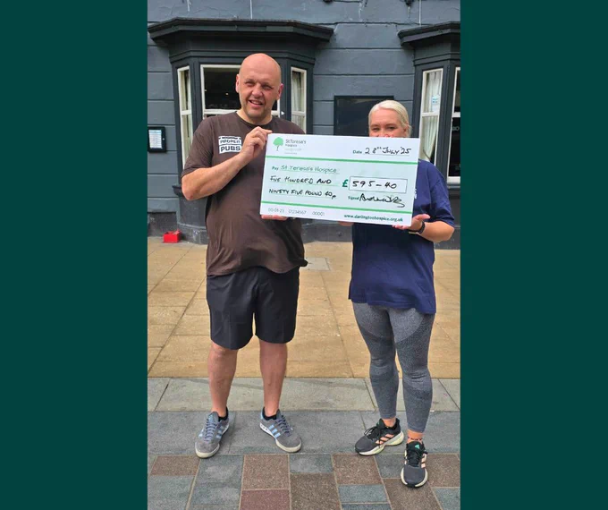 A man and a woman holding a cheque for £595.40 outside Rosie's Tavern in Darlington.