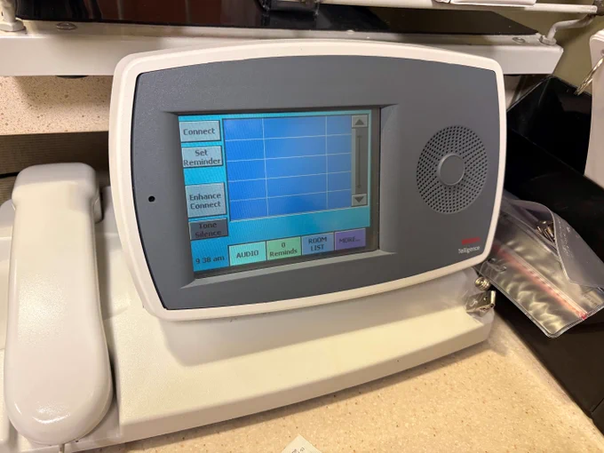 An older model Ascom nurse call console sitting on a nurse's station in a hospital. 