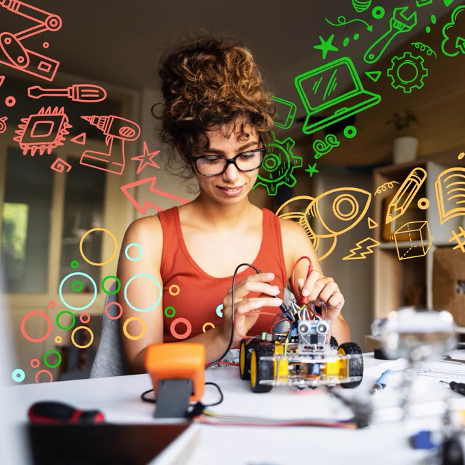 A young woman with curly hair and glasses is working on a robot car project at a table covered in tools and wires. Colorful icons float around her, showing things like a rocket, laptop, book, and wrench to represent education and creativity. 