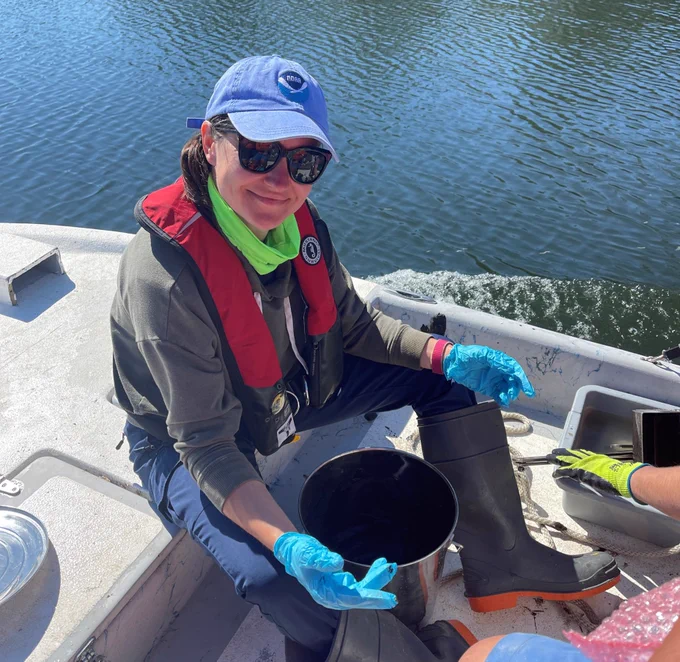 Woman sits on a boat holding a bucket