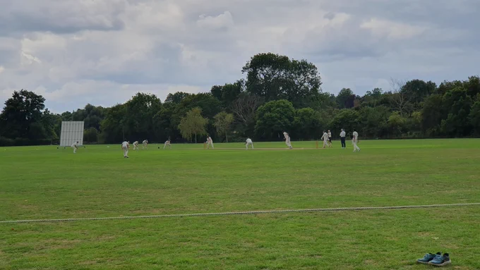 View from boundary shows slip, gully and other fielders watching on as batter tries to hit ball as umpire looks on