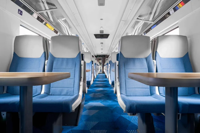 Image: Inside of MK5 train blue steas with a table infront and blue carpets. 