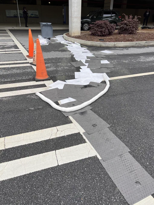 Traffic cones line  a crosswalk and absorbent pads cover parts of the road 