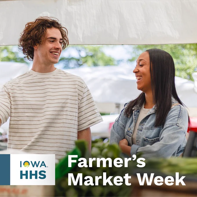 Two people smiling and talking at a farmer's market during Iowa Farmer's Market Week.