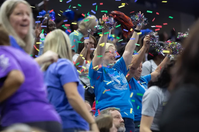 confetti falling with people in blue and purple shirts smile